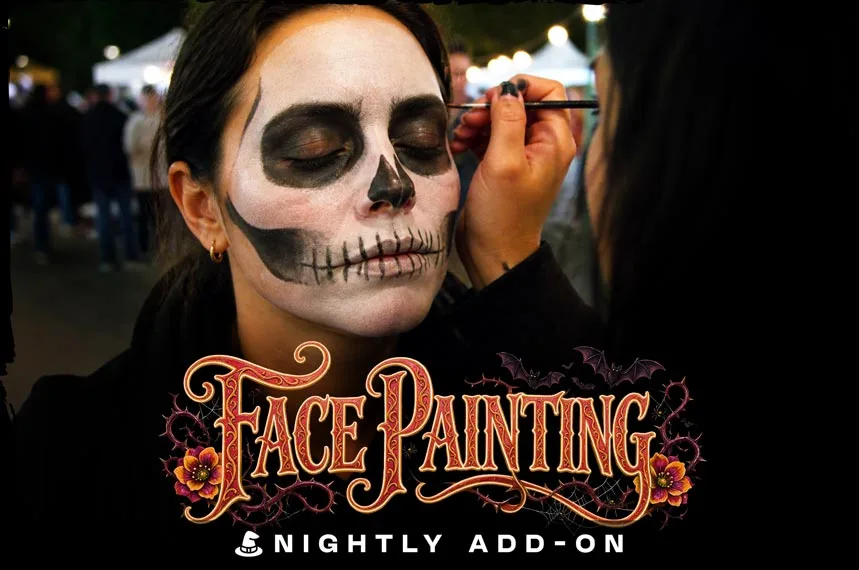 Close-up portrait of a woman with her eyes softly closed as a makeup artist uses a fine brush to apply intricate, black-and-white skull face paint to her features.