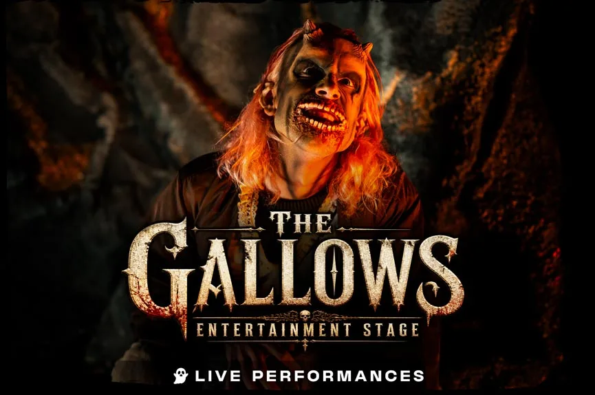 A demonic, blood-soaked actor with small horns, stringy hair, and a terrifyingly wide, exposed-jaw grin staring intensely into the camera.