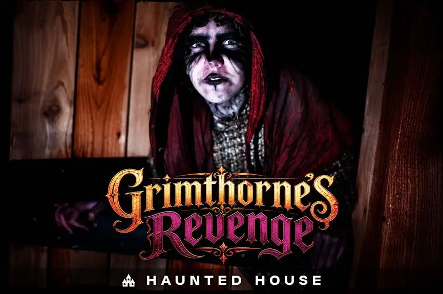 A spooky figure shrouded in a tattered red hood with blackened eye makeup peering out from a dark wooden doorway for Grimthorne's Revenge Haunted House.