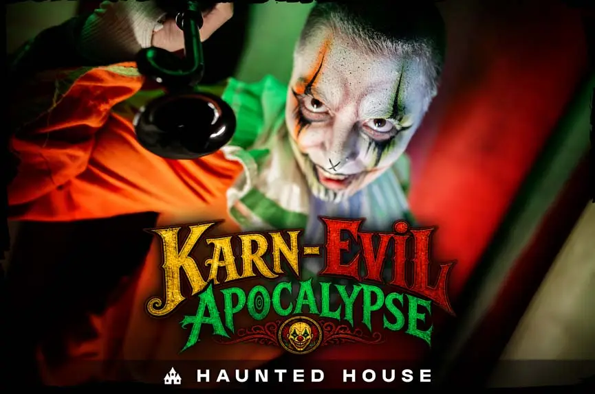 Close-up of a sinister, grinning clown with green and orange makeup holding a black horn against a red background for the Karn-Evil Apocalypse Haunted House.